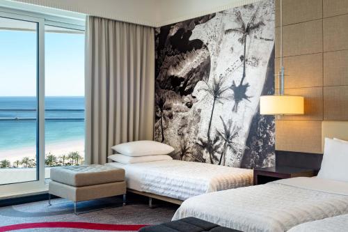 two beds in a room with a view of the ocean at Le Meridien Al Aqah Beach Resort in Al Aqah
