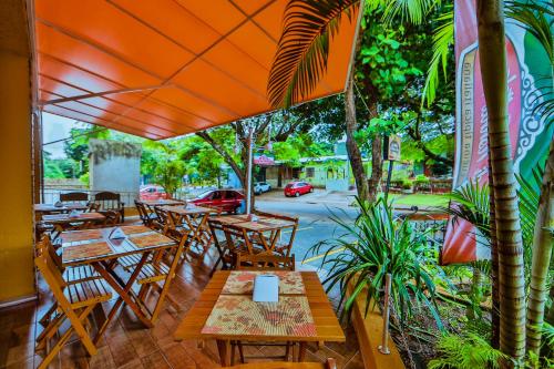 ein Restaurant im Freien mit Holztischen, Stühlen und Bäumen in der Unterkunft Pousada Iguassu Charm Suites in Foz do Iguaçu