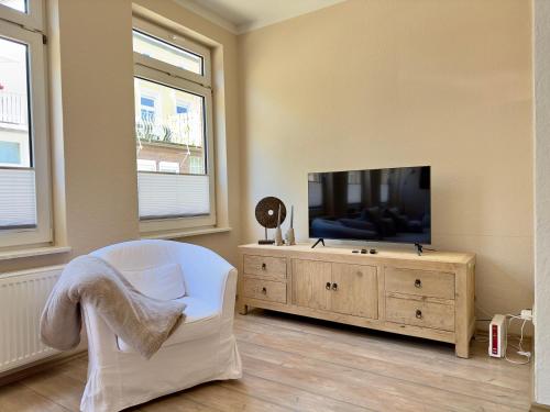 ein Wohnzimmer mit einem TV und einem weißen Stuhl in der Unterkunft Seestern in Warnemünde