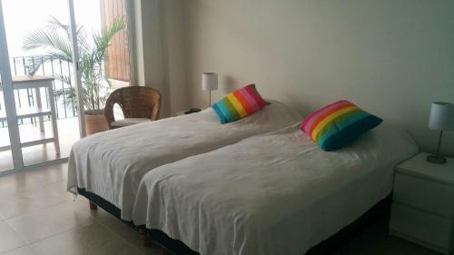 1 cama blanca con 2 almohadas de colores en una habitación en Playas Gemelas Puerto Vallarta, en Puerto Vallarta
