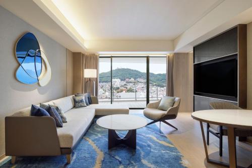 uma sala de estar com um sofá e uma televisão em Nagasaki Marriott Hotel em Nagasaki
