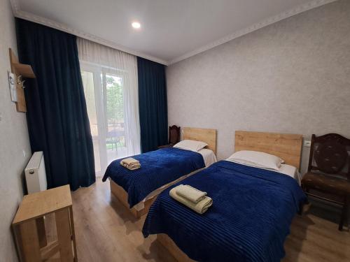 1 Schlafzimmer mit 2 Betten mit blauer Bettwäsche und einem Fenster in der Unterkunft Guest House Akhaltsikhe in Achalziche