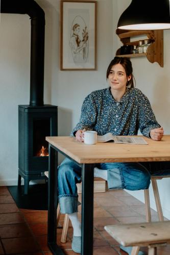 a woman sitting at a table in front of a stove at Mountain house Ebner in Selva dei Molini