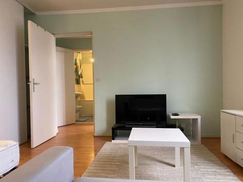 - un salon avec une télévision et une table blanche dans l'établissement Appart calme avec parking gratuit, à Évry-les-Châteaux