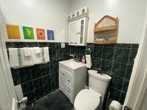 uma casa de banho com um WC branco e um lavatório. em Harmony place to stay close to all fun in Jersey at 15 minutes to NY City em North Bergen