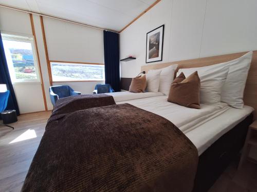 een slaapkamer met een groot bed met kussens bij Tjeldsundbrua Hotel in Evenskjer