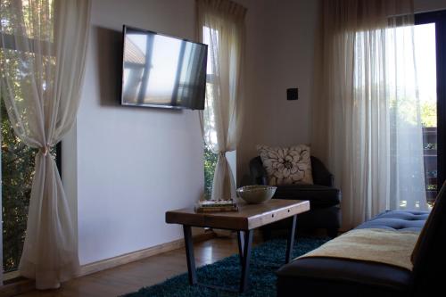 a living room with a table and a tv on the wall at Treetop Guesthouse in Gqeberha