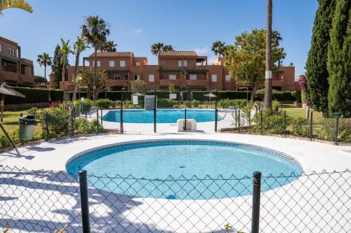 una valla en la piscina con una valla alrededor en Precioso Apartamento Jardin del Golf 1, Novo Sancti Petri, en Chiclana de la Frontera