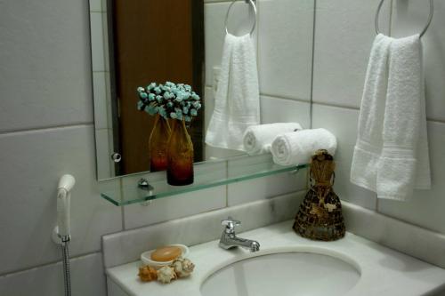 a bathroom with a sink and a mirror and towels at Pousada Restinga Apart Service- Aeroporto in Lauro de Freitas