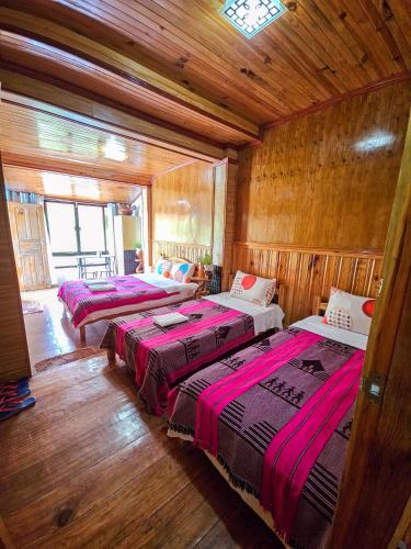 three beds in a room with wooden walls at Banaue Rice Homestay in Banaue
