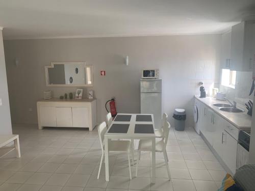 a white kitchen with a table and chairs in it at Frente á Praia in Portimão
