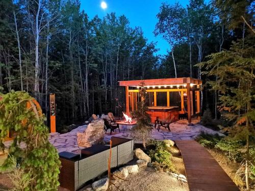 a house in the woods with a fire pit at ONNEA - Magical Chalet with Stunning Views, Sauna & Hot Tub in Petite-Rivière-Saint-François