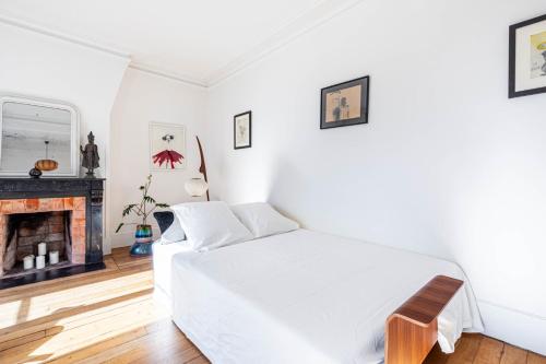 une chambre blanche avec un lit et une cheminée dans l'établissement GuestReady - A Zen haven near Montmartre, à Paris