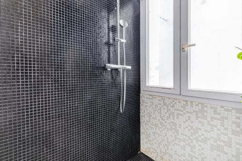 La salle de bains est pourvue d'une douche avec du carrelage noir. dans l'établissement GuestReady - A Zen haven near Montmartre, à Paris