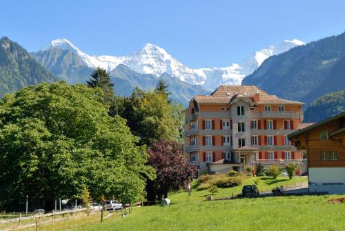 un edificio en un campo con montañas en el fondo en Hotel Berghof Amaranth, en Wilderswil