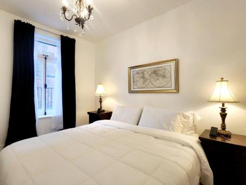 a bedroom with a large white bed and a window at Old Quebec - Les Suites Montcalm - Free Parking in Quebec City