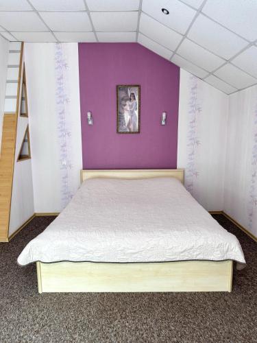 1 dormitorio con 1 cama grande y pared morada en Hotel Vesta en Brovary