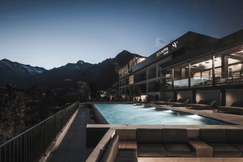 um edifício com uma piscina com montanhas ao fundo em SomVita Suites em Tirolo
