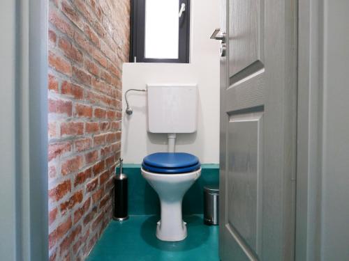 a bathroom with a blue toilet with a brick wall at Choco Home & Hostel in Cluj-Napoca