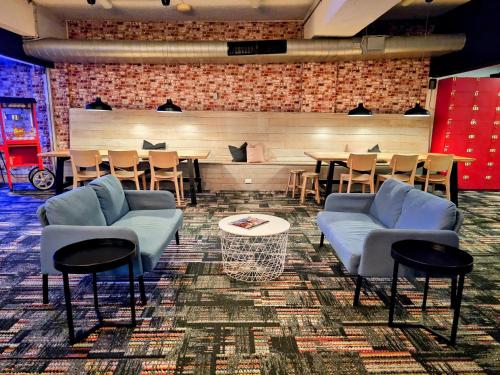 un restaurante con sofás azules, mesas y sillas en Trademark Hostel Sydney en Sídney