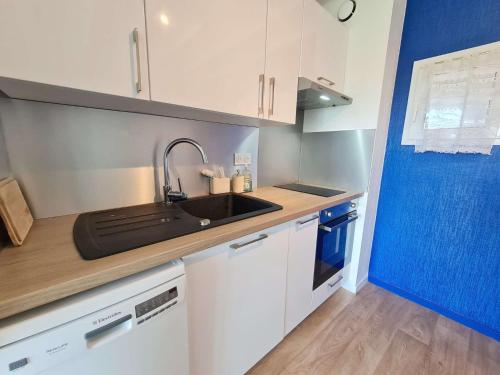 - une cuisine avec un évier et des placards blancs dans l'établissement Ref 051 - Appartement T3 pour quatre avec piscine et internet, à Arzon