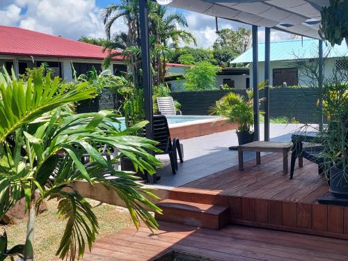 eine Holzterrasse mit einer Bank und einem Tisch in der Unterkunft "Koko Lodge" Lodge paisible avec terrasse, jardin et piscine in Rémiré