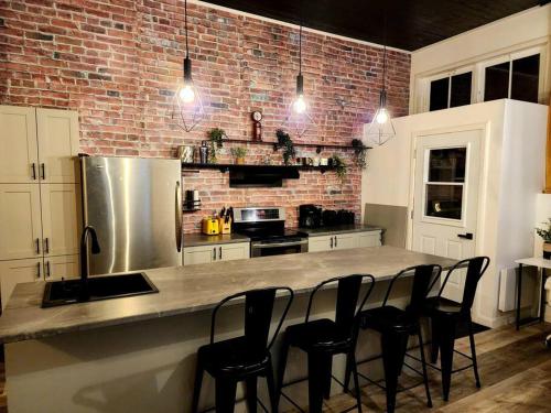 a kitchen with a counter with chairs and a brick wall at Loft Style Industriel Centre ville Parking Gratuit in Quebec City