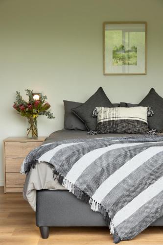 a bedroom with a bed and a vase of flowers at Askop Hilltop Farm House The Crags Plettenberg Bay in The Crags