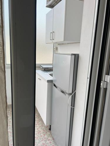 a kitchen with white cabinets and a refrigerator at Guesthouse Butrinti in Ksamil