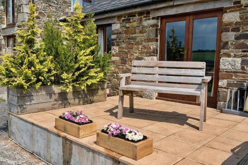 a wooden bench sitting on a patio with flowers at Finest Retreats - The Shippon at Lestitha in Liskeard