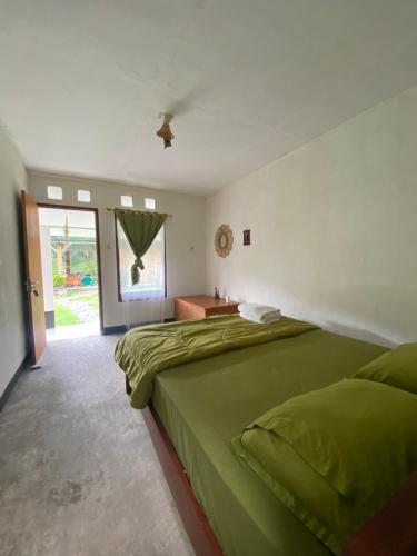 een slaapkamer met een groot groen bed en een raam bij Rago's Homestay in Kelimutu