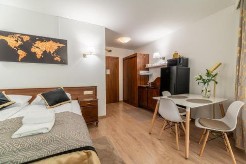 a bedroom with a bed and a table and a small kitchen at AL-DOM apartamenty Apartament GOLD in Kołobrzeg