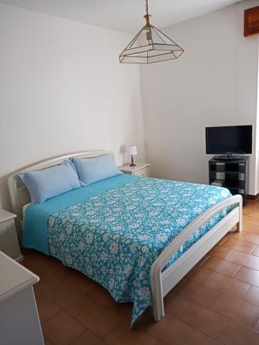 a bedroom with a bed with a blue comforter and a television at Casa Lino in Monserrato
