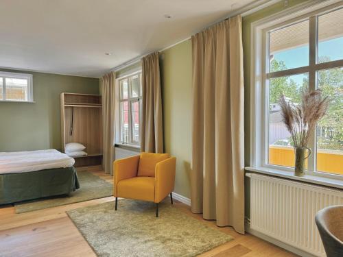 een slaapkamer met een bed, een stoel en een raam bij Hotell Magasin 1 in Mörbylånga