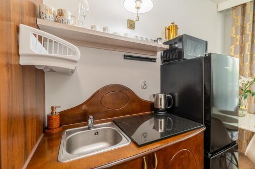 a kitchen with a sink and a refrigerator at AL-DOM apartamenty Apartament GOLD in Kołobrzeg