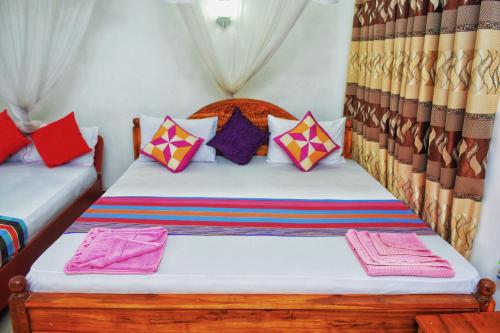 - une chambre avec 2 lits et des oreillers colorés dans l'établissement Passion Ray Villa & Tree Hut, à Sigirîya