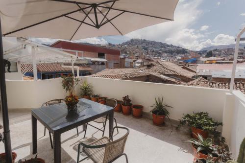 uma mesa e cadeiras numa varanda com um guarda-sol em Quechua ApartHotel em Cusco