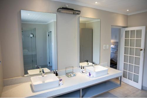 La salle de bains est pourvue de 2 lavabos et de 2 miroirs. dans l'établissement Macaron Boutique Guest House, à Franschhoek