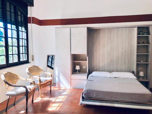 a bedroom with a bed and two chairs at Villa I Tigli Appartamenti in Campiglia Marittima