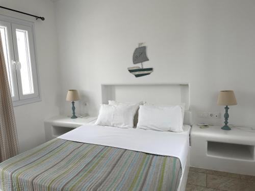 a white bedroom with a bed and two tables and a window at MAGGANARI MOMENTS 2 in Manganari