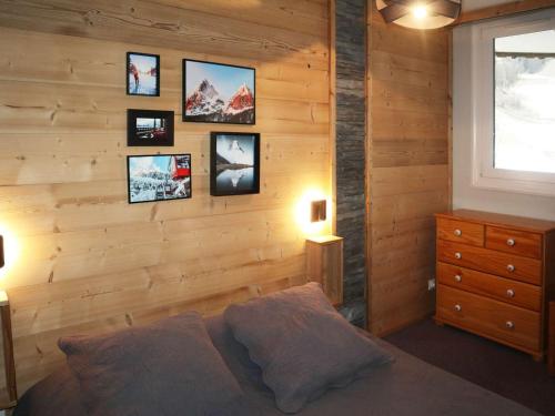 une chambre avec un mur en bois avec des tableaux sur le mur dans l'établissement Appartement accueillant pour 6 personnes au cœur des Orres - FR-1-322-18, aux Orres