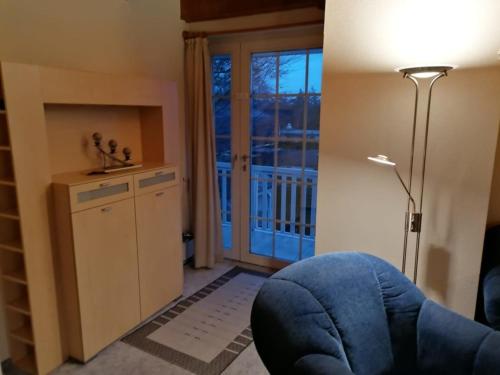 a living room with a blue chair and a sliding glass door at Kampweg 1 Wohnung 1 in Cuxhaven