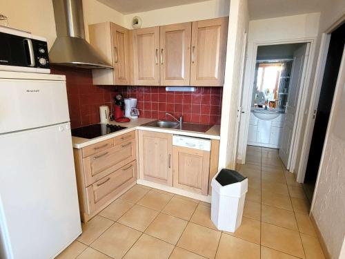 une cuisine avec des armoires en bois et un évier dans l'établissement Appartement Sud 6 pers avec Terrasse, WiFi, et Parking Optionnel - Animaux Admis - FR-1-393-32, à Saint-Michel-de-Chaillol