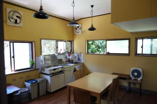 a kitchen with yellow walls and a table and windows at 奈良吉野の小学校跡地ゲストハウス-五右衛門風呂体験-漫画図書室-卓球台-一棟貸し-素泊まり-吉野山天川村観光-Small inn attached to a historic school building in Zengi