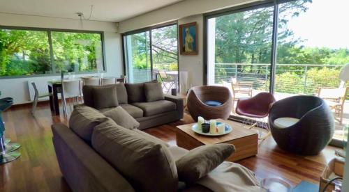 un salon avec un canapé, des chaises et des fenêtres dans l'établissement La Muse Basque Villa, à Arbonne