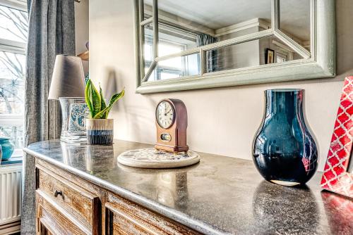 a counter with a blue vase and a clock on it at Comfortable Home in Wandsworth by UndertheDoormat in London