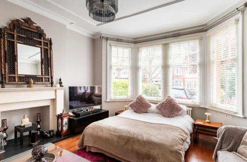 a bedroom with a bed and a fireplace and a tv at Luxury 6 Double Bedroom London Town house in Ealing