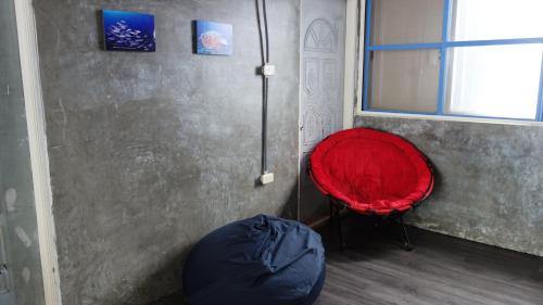 a red chair sitting in a room with a window at Lanyu Blue Capsule in Lanyu