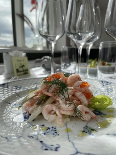 a plate of shrimp on a table with wine glasses at Badehotellet Grenaa Strand in Grenå
