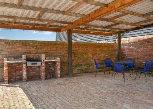 un patio con sillas azules, una mesa y una pared de ladrillo en Hill Farm Retreat en Wangford